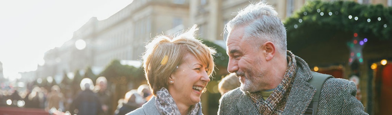 Older couple smiling at each other while outside on a street front 